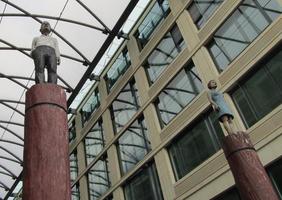 Wooden sculptures of man and woman, also atop wooden poles