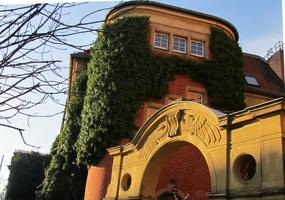 Sunlit stone arch in foreground; ivy-covered library in background