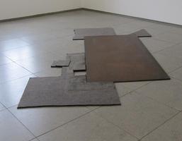 Irregularly shaped flat pieces of metal lying on floor