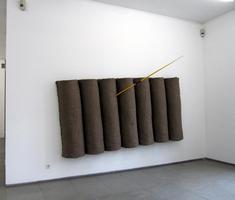rolls of brown cloth with yellow needle stuck through one of them at a 30 degree angle