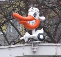 Cartoonish duck in a car on top of a car rental agency.