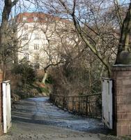 Open gate and path in foreground; 5-story building in background