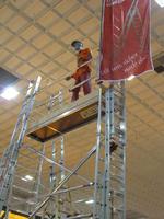 Mannequin dressed in work clothes atop a high platform with ladders
