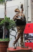 Standing man, arm extended, as if eating grapes