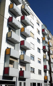 Building with balconies whose shorter sides are yellow and red.