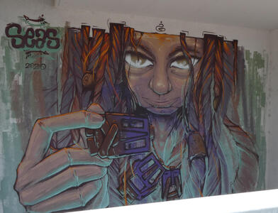 Person with long hair,staring at viwer and  holding a necklace toward the viewer
