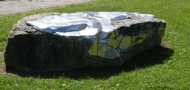 Large rock with irregular reflective surfaces.