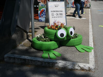 Frog with large googly eyes; made of three car tires painted green.