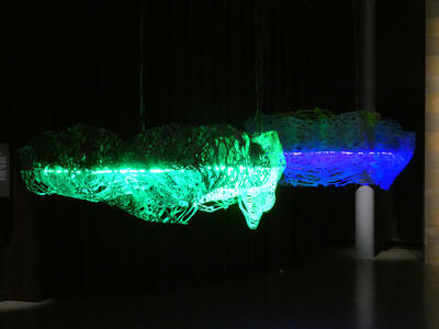 Green and blue rock-like sculptures hanging from ceiling.