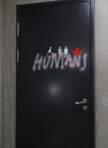 Restroom entrance with HUMANS spray-painted on door in pink