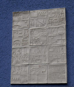 Blue stucco walls with white tiles; the tiles have heiroglyphics on them.