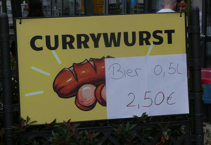 Currywurst sign; on top of it is paper sign reading Bier 0,5L 2,50€