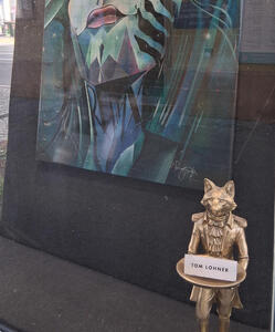 Bronze fox in butler outfit, holding tray with business card for artist Tom Lohner.