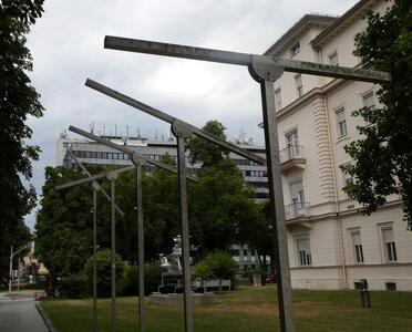 Row of vertical poles. At top of each pole is a crossbar. The crossbars are all at different angles.