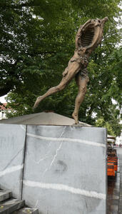 Abstract sculpture of person walking with hands behind back.