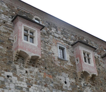 Windows in brick structures protruding from stone castle wall