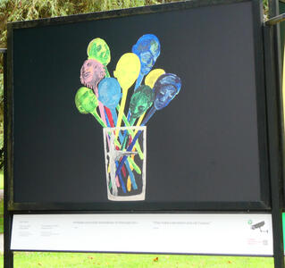 Glass holding what appear to be spoons, but the bowls are people’s faces