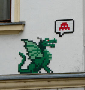 pixel art of a green dragon emitting a word balloon with a space invader icon in it