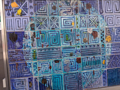 Blue and turquoise tiles with rectangular lines and spirals carved on them.