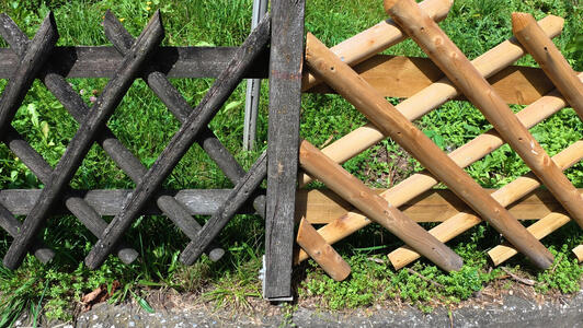 Partial replacement of a fence. On the left, old, worn wood; on the right, brand-new wood