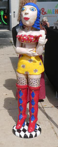 Ceramic statue of woman with blue hair, red halter top, yellow skirt, and high red boots