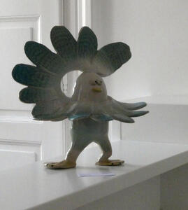 Whimsical bird with smiling face and feathers spread in a semicircle