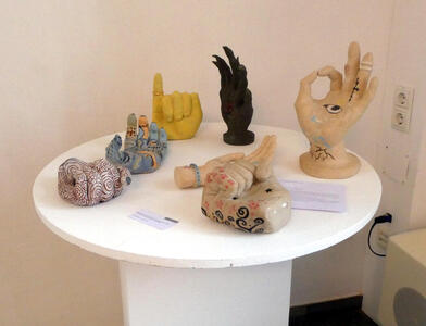 Seven ceramic sculptures of hands painted in various themes.