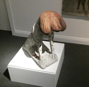 Sculpture of dog with brown head and long floppy ears; body of dog is white with brown spots.