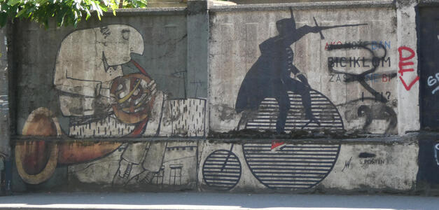 At left, man playing a french horn. At right, a soldier on a pennyfarthing bicycle pointing a sword to the right.