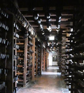 Racks of rifles on both sides of a hall; helmets hanging from a beam between the two sides.