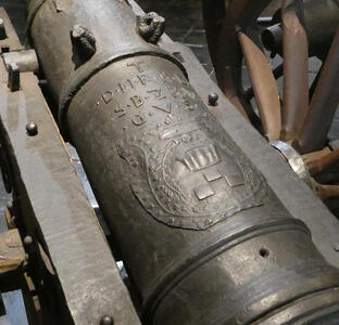 Closeup of cannon barrel showing lettering and a coat of arms