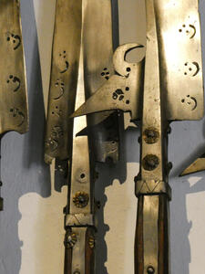 Closeup of bronze-colored spears showing metalwork with what appear to be arabic letters.