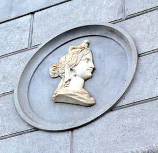 Round stone piece on a wall with a relief-work woman’s head