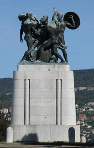 Monument showing people in battle. One is holding a shield.