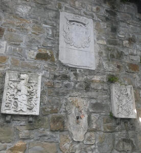 Four coats-of-arms attached to a brick wall.