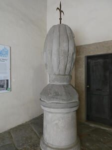 Top of a plinth. It is a football-shaped stone with a ribbed design, looking much like a melon