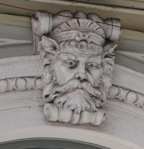 Relief carving of man’s head. Man has beard, pointed ears, and a grim expression