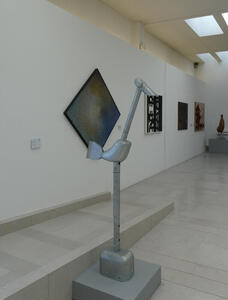 Tall metal abstract bird sculpture with long neck and legs, short body and tail