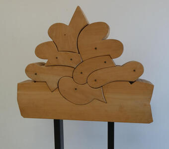 Wooden sculptue that looks like a group of fish, animal, and bird=shaped puzzle pieces