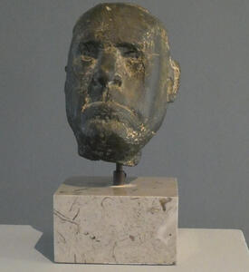 Bronze sculpture of a man’s head; the man is frowning