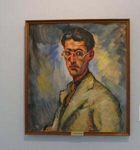 Oil on canvas portrait of man wearing a tan jacket. He has round glasses and black hair, and a thin face.