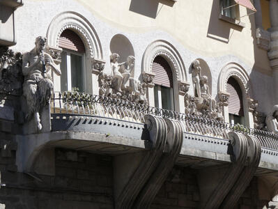 Statue of Pan at left; children are seated in niches between the windows, looking out at the street