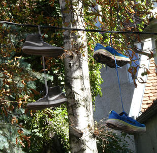 One pair of gray sneakers and a pair of blue sneakers hanging over a line