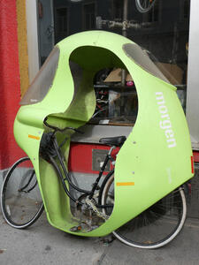 Bicycle with green plastic/metal shell to protect rider from wind and rain