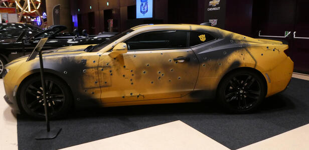 Yellow Chevrolet with black areas as if the car had been burned, and “bullet holes” in the doors.