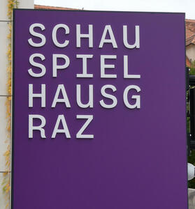 sign divided into four lines: SCHAU / SPIEL / HAUSG / RAZ