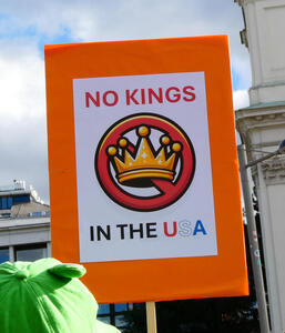 No Kings in the USA. Has drawing of a crown with the slash of a “no” circle through the interior of the crown.