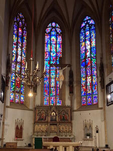 Stained glass windows behind altar. A crucifix is above the altar