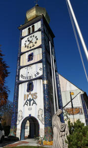 Front of church. From top, gold dome with cross, clock, sundial, and archway.