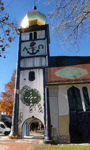 Side of church tower. At top, an anchor with letters lambda and omega; at bottom, a person on knees praying in front of a cross.